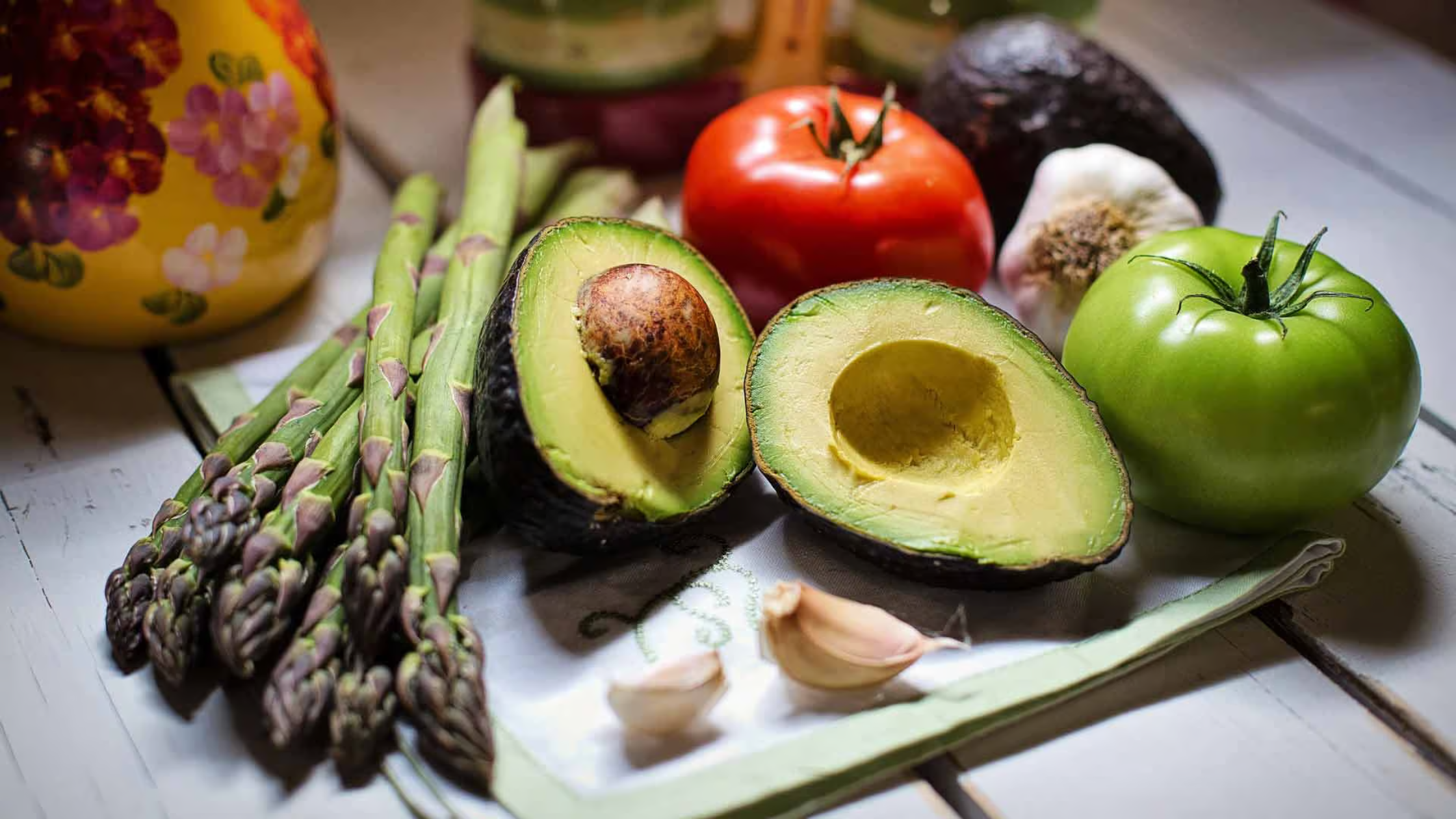 Aguacate, espárragos, tomate y ajo en una pesada de madera