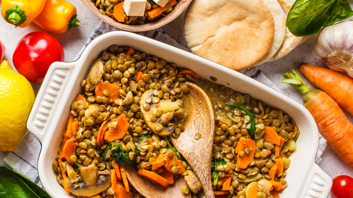 Cazuela lentejas, verduras y champiñones, vegetales coloridos a los costados y pan