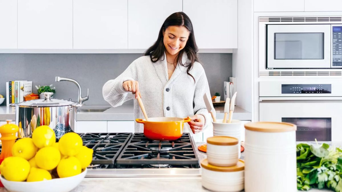Una persona sonriente, cocinando en una cocina luminosa