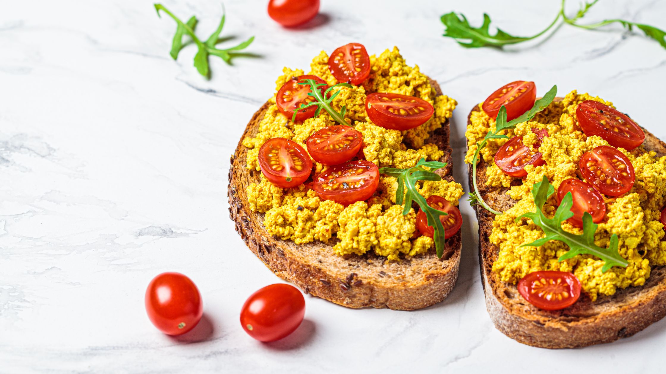 Tofu revuelto en tostada con tomate y rúcula
